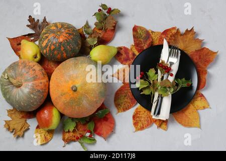 Mise en table le jour de Thanksgiving décoré de citrouille, de viburnum, de poires et de feuilles colorées sur le gris. Vue de dessus Banque D'Images