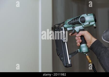 Carpenter en utilisant de l'air pistolet installation d'installer dans la nouvelle porte Banque D'Images