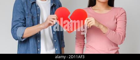 Gros plan d'un jeune couple tenant un cœur rouge cassé Banque D'Images