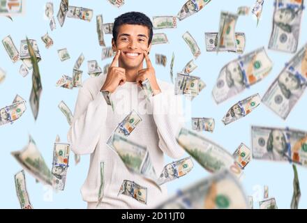 Jeune homme amérindien africain portant des vêtements décontractés souriant à la bouche ouverte, les doigts pointant vers le haut et forçant le sourire joyeux Banque D'Images