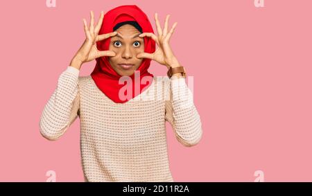 Jeune afro-américaine portant un foulard islamique traditionnel de hijab essayant d'ouvrir les yeux avec les doigts, endormie et fatiguée pour la fatigue matinale Banque D'Images