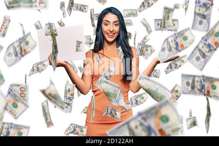 Belle femme hispanique tenue vide bannière vide vierge célébrant la victoire avec sourire heureux et expression du gagnant avec les mains levées Banque D'Images