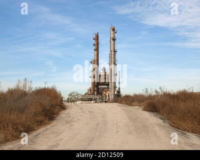 Vue sur l'ancienne tour de raffinerie de pétrole industriel et de pétrochimie sur une route rurale vide. Banque D'Images