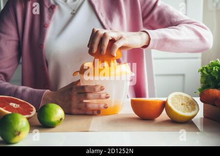 Gros plan d'une femme qui fait du jus à la maison il n'y a plus de fruits à l'aide d'un presse-fruits manuel Banque D'Images