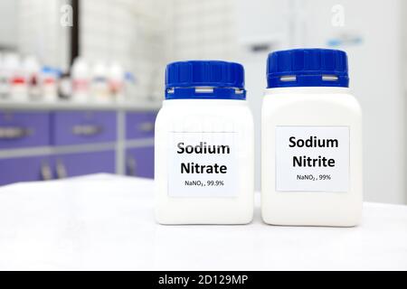 Mise au point sélective de flacons de nitrite de sodium pur et de composé chimique de nitrate conservateur. Fond blanc de laboratoire avec espace de copie. Banque D'Images