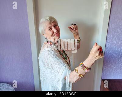 Joyeux sourire drôle femme âgée portant des perles dansant à la maison Banque D'Images