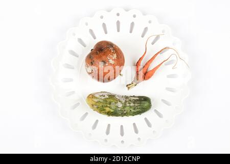 pomme pourrie, concombre, carotte sur plaque sur fond blanc. problème de faim dans le monde. concept de surconsommation. vue du dessus copie espace bannière Banque D'Images