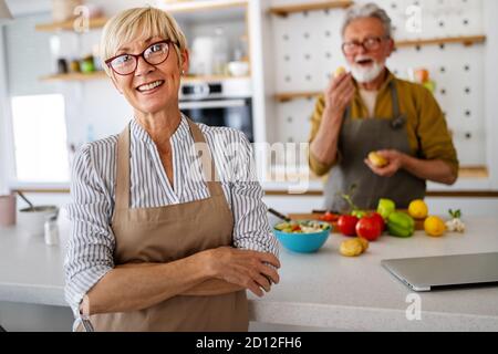 Couple senior s'amuser, cuisiner ensemble dans la cuisine maison Banque D'Images