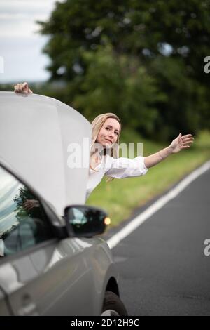 Jolie femme d'âge moyen ayant des problèmes de voiture - voiture cassée sur le côté de la route, appelant la compagnie d'assurance pour l'aide Banque D'Images