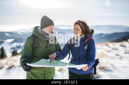 Les randonneurs en couple senior utilisent la carte dans la nature enneigée de l'hiver. Banque D'Images