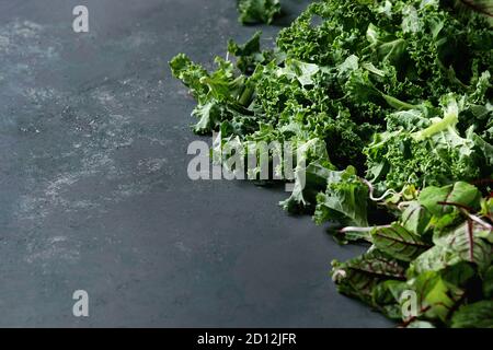 Salade verte mélange salade ou smoothie with kale, de jeunes feuilles de betterave, pousses, plus de surface texture sombre. Copier l'espace. Arrière-plan de l'alimentation. Banque D'Images
