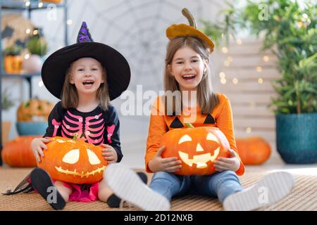 Mignons petites filles avec la sculpture de citrouille. Bonne famille se préparant pour Halloween. Enfants amusants à la maison. Banque D'Images