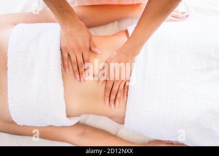 Une femme se fait masser le ventre dans une salle de procédure lumineuse. Massage anti-cellulite, diastase. Banque D'Images