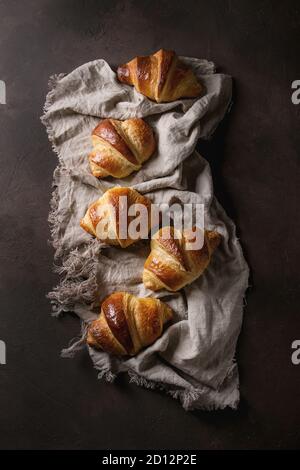 Des petits croissants traditionnels sur tissu en lin brun foncé sur fond de texture. Vue de dessus, de l'espace Banque D'Images