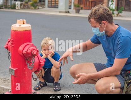 Influence de père son vision du monde éducation familiale étudier les compétences quotidiennes de connaissances. Papa en bleu COVID masque de visage montrer dire enseigner aux enfants pompiers combattants Banque D'Images