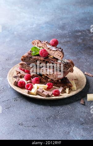 Des tranches de pizza au chocolat dessert sucré avec différents chocolats, framboises et menthe servi sur une plaque en céramique bleu sur fond de texture. Co Banque D'Images