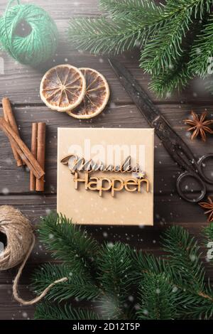 Boîte cadeau de Noël avec lettres en bois miracles se produisent. Idées d'emballage de cadeaux. Design naturel. Banque D'Images