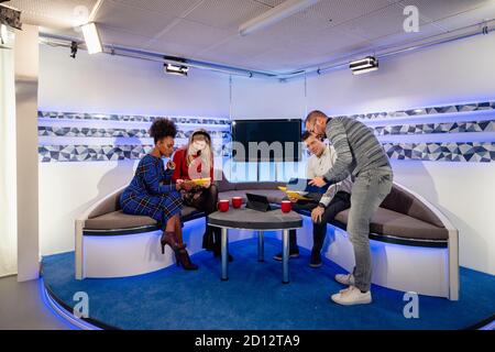 Une émission de télévision en cours de tournage dans un studio. Les présentateurs sont assis sur le canapé du studio tout en regardant les notes qui leur sont données par le produit Banque D'Images