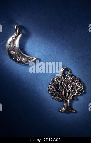 La Lune et l'arbre, pendentifs païens d'argent, symboles de la religion wiccan sur fond bleu foncé Banque D'Images