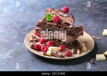 Des tranches de pizza au chocolat dessert sucré avec différents chocolats, framboises et menthe servi sur une plaque en céramique bleu sur fond de texture. Co Banque D'Images