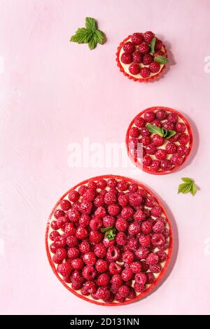 Variété de framboise rouge tartes et tartelettes sablés crème au citron et framboises fraîches émaillés rose sur fond pastel. Vue de dessus, de l'espace. Banque D'Images