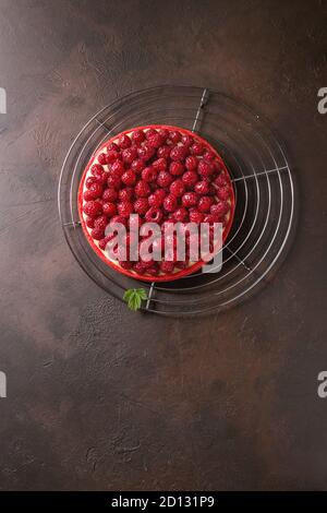 Tarte sablée framboise rouge et crème de citron framboises fraîches servi glacé sur grille de refroidissement sur dark brown texture background. Vue de dessus, la CDP Banque D'Images