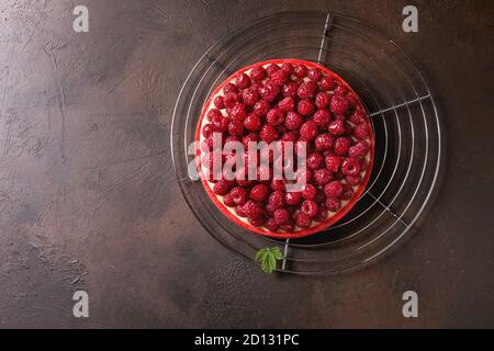 Tarte sablée framboise rouge et crème de citron framboises fraîches servi glacé sur grille de refroidissement sur dark brown texture background. Vue de dessus, la CDP Banque D'Images