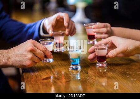 Cocktail à la discothèque. Groupe d'amis tequila shot verres au bar. Mains mâles verres de grenaille ou de liqueur. Les amis boivent une dose ou une liqueur. Cinq Banque D'Images