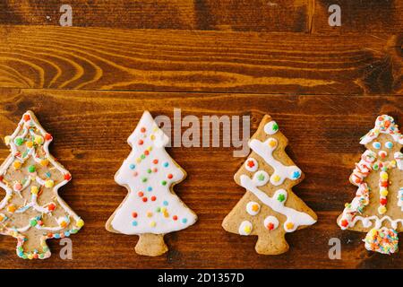 Quatre biscuits au pain d'épice en forme d'arbres de Noël, décorés de glace et de saupoudriers. Banque D'Images