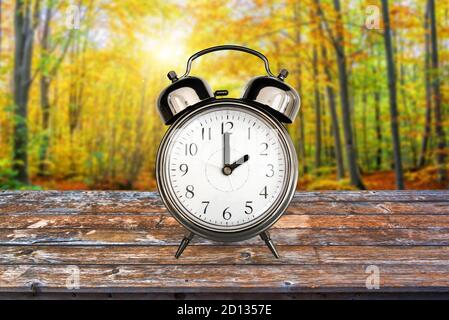 Vintage clock in a forest in autumn. Fall daylight savings time change concept Banque D'Images