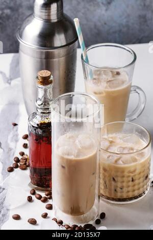 Cocktail café glacé frappe) avec des cubes de glace et de la crème dans des verres avec silver shaker, bouteille de rhum, les grains de café autour de marbre blanc sur ta Banque D'Images