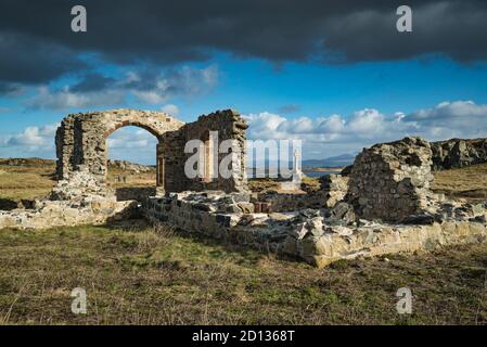 Des nuages sombres surplombaient les ruines ensoleillées de l'église St Dwynwen, sur la péninsule de Llanddwyn, à Anglesey Banque D'Images