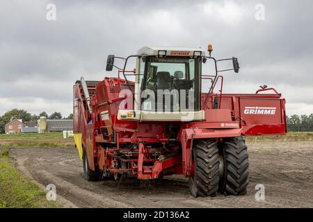 HOGE HEXEL, PAYS-BAS - 30 août 2020 : vue frontale de la machine lourde de la récolteuse de pommes de terre dans le sol agricole prêt à recueillir la récolte avec la ferme dans le bac Banque D'Images