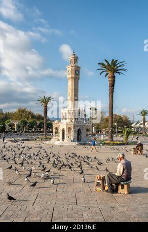 Homme turc senior non identifié vendant de la nourriture pour pigeons près de la Tour de l'horloge d'Izmir sur la place Konak en Turquie Banque D'Images