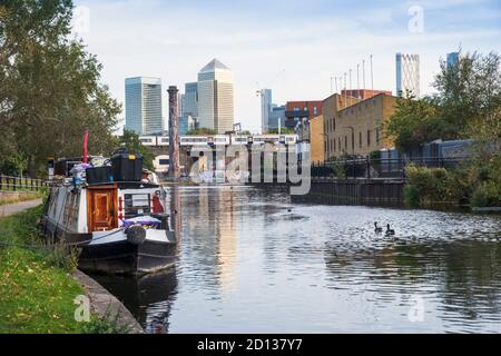 Londres, Hackney. Bateaux étroits sur le canal Regent's avec les tours du quartier financier de Canary Wharf au loin Banque D'Images