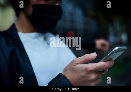 détail de la main de la femme avec le téléphone. sur le visage portant un masque à temps du virus corona Banque D'Images