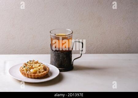 Sablés aux pommes faite maison à tartelette plaque blanche, verre de thé chaud en vintage porte-gobelet sur la table de marbre blanc. L'automne à la cuisson. Style minimaliste. Banque D'Images