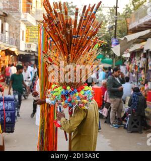 Un homme vendant des flûtes et des jouets en plastique, exposé sur son épaule dans les rues de Pushkar, Rajasthan, Inde, le 10 novembre 2018 Banque D'Images
