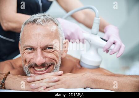 Smiley senior citoyen posant sur son ventre pendant les procédures cosmétiques Banque D'Images