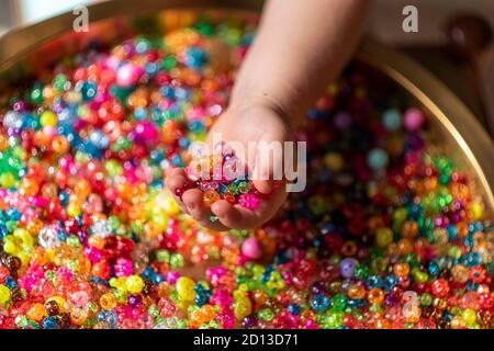 Perles de couleur dans les paumes de l'enfant. Un fond très coloré de perles étincelantes Banque D'Images