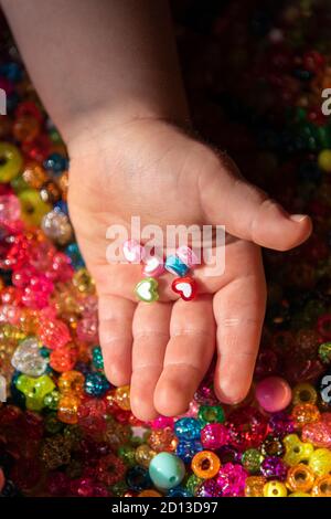 Perles de couleur dans les paumes de l'enfant. Un fond très coloré de perles étincelantes Banque D'Images