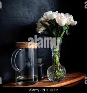 Des pivoines blanches magnifiques et luxuriantes dans un vase sur fond noir, bouquet à la maison. Banque D'Images