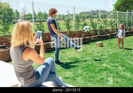 Mère de prendre photo de son mari et son fils jouer Banque D'Images