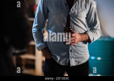 amis les gars se sont réunis à une fête de baccalauréat dans le garage, buvant de la bière de bouteilles sombres à une fête Banque D'Images