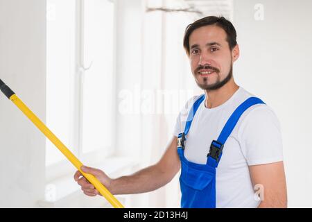 Grenaille moyenne, constructeur en bleu vêtements de travail peint mur dans l'appartement Banque D'Images