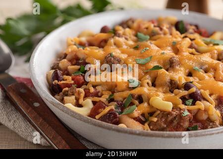 Gros plan du bol de macaroni au Chili avec du fromage cheddar fondu sur une table en bois Banque D'Images