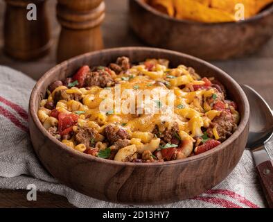 Gros plan du bol de macaroni au Chili avec du fromage cheddar fondu sur une table rustique en bois Banque D'Images