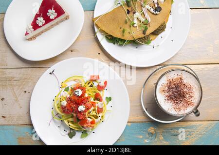 Déjeuner sain, pâtes de courgettes, crêpe végétale et café cappuccino, sur une table en bois, vue sur le dessus. Banque D'Images