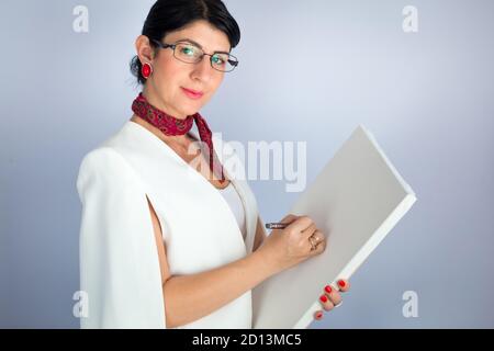 Un élégant professeur de brunette montrant quelque chose sur un tableau blanc vide. Formation en ligne Banque D'Images