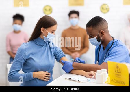 Médecin effectuant l'injection du vaccin contre le coronavirus à la femme enceinte à l'hôpital Banque D'Images